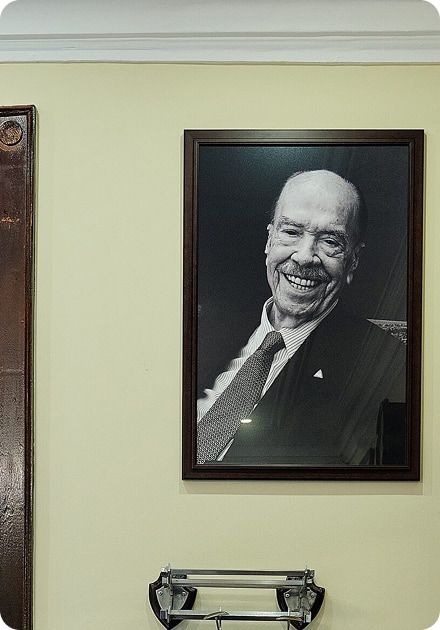 A black and white framed portrait of a smiling man in a suit and tie.