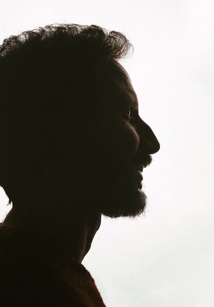 Side profile silhouette of a bearded man against a bright, plain background