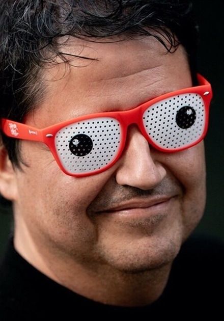 Smiling man wearing red googly eye glasses.
